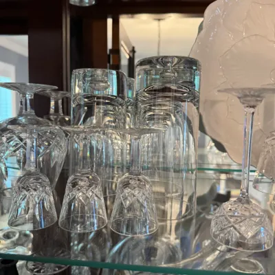 Sale Photo Thumbnail #248: Assorted vintage crystal stemware and glassware displayed on a glass shelf inside a wooden china cabinet.