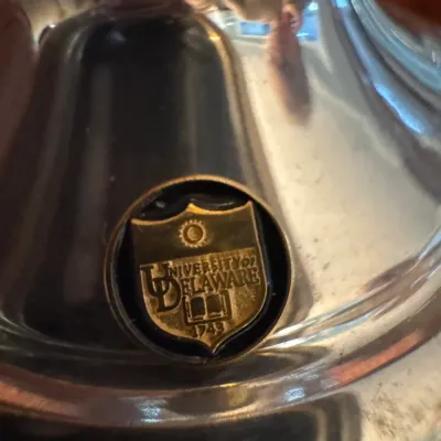 Sale Photo Thumbnail #250: Polished silver-plated vessel featuring an inset brass University of Delaware seal medallion.