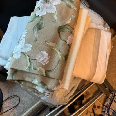 Sale Photo Thumbnail #170: Assorted vintage textiles and fabrics, featuring a prominent roll of tan floral upholstery fabric with white lilies and green leaves.