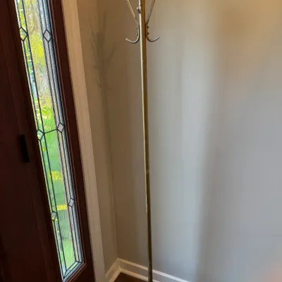 Vintage brass coat rack featuring a slender pole, multiple curved hooks at the top, and a weighted circular base.