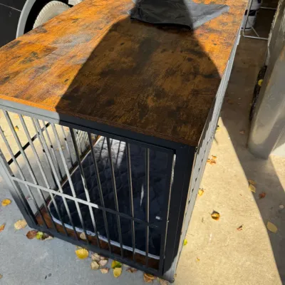 Modern industrial-style dog crate furniture piece with a rustic brown wooden top, black metal frame, and an included interior dog bed.