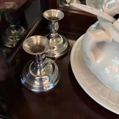 Pair of vintage silver-plated candlestick holders with small gold-colored maker's marks, displayed on a dark wood surface next to a...
