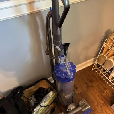 Sale Photo Thumbnail #227: Dyson Ball upright vacuum cleaner in grey and blue, accompanied by a bag of attachments and accessories.