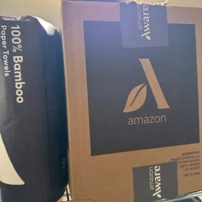 Sale Photo Thumbnail #104: Amazon Aware cardboard box and a package of 100% Bamboo Paper Towels sitting on a wire shelf.