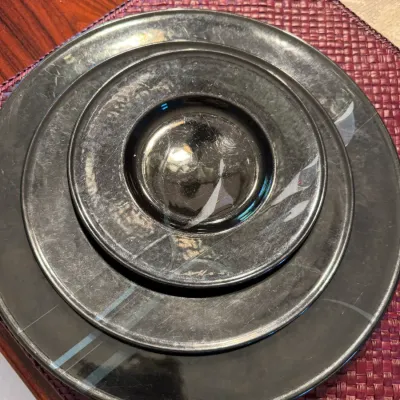 Sale Photo Thumbnail #270: Three-piece set of black glass dinnerware, including a dinner plate, salad plate, and saucer, featuring a subtle white swirl design.