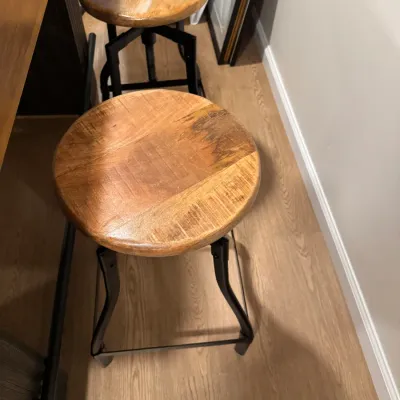 Pair of industrial-style swivel bar stools featuring round wooden seats and black metal frames.