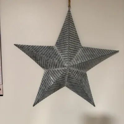 Sale Photo Thumbnail #110: Rustic corrugated galvanized metal barn star wall hanging, featuring a five-point design and a jute rope hanger.