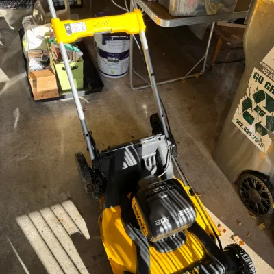 Sale Photo Thumbnail #210: DeWalt 20V Max cordless lawn mower in yellow and black, showing light use and stored in a garage.