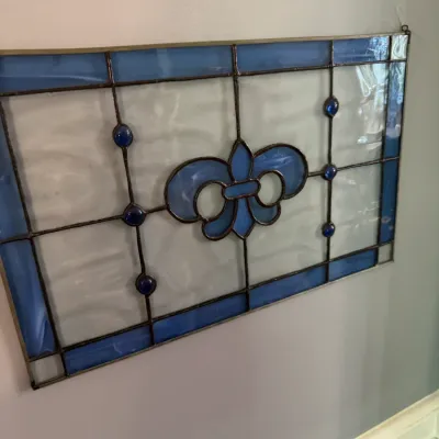 Sale Photo Thumbnail #231: Rectangular stained glass window panel featuring a blue fleur-de-lis motif, blue borders, and glass gem accents on a textured clear glass background.