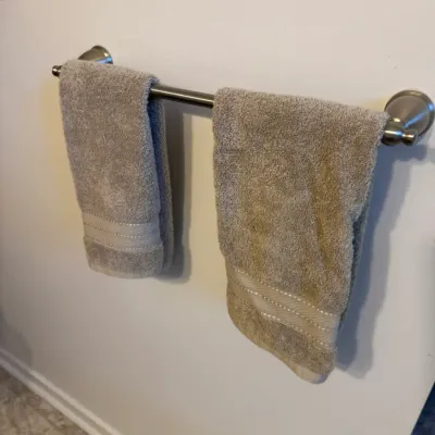 Sale Photo Thumbnail #127: Two beige cotton hand towels with decorative woven borders hanging on a brushed nickel towel bar.