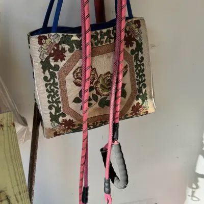 Sale Photo Thumbnail #202: Vintage tapestry tote bag with floral rose design and blue handles, shown hanging alongside pink rope dog leashes.