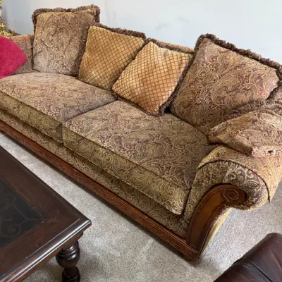 Sale Photo Thumbnail #257: Traditional rolled-arm sofa featuring ornate paisley upholstery in gold and burgundy tones, complete with matching fringed throw pillows and a carved wood base.