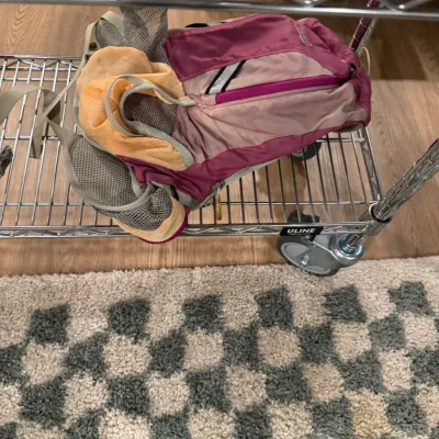 Sale Photo Thumbnail #115: Pink, orange, and grey hydration pack backpack resting on a wire rolling cart.