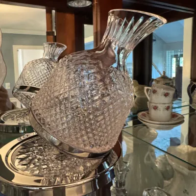 Vintage cut glass decanter with a silver-plated base, designed to tilt on a matching silver-plated stand.