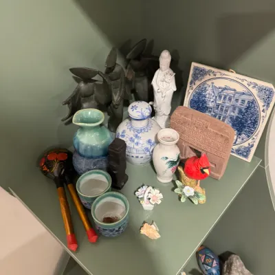 Sale Photo Thumbnail #282: Assorted collection of small decorative items, including a blue and white ceramic ginger jar, a Delft-style tile, a cardinal figurine, and various small vases and sculptures.