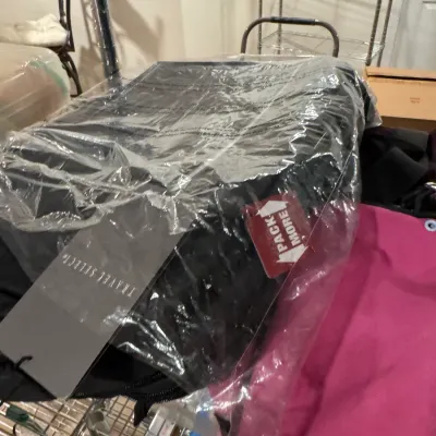 Travel Select black luggage piece, new in original plastic packaging with tags attached.