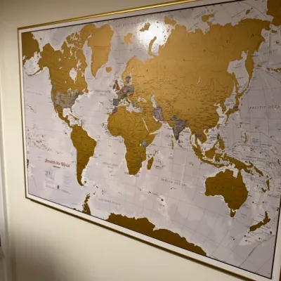 Large framed "Scratch the World" travel map with a gold-colored frame, showing partially scratched-off regions.