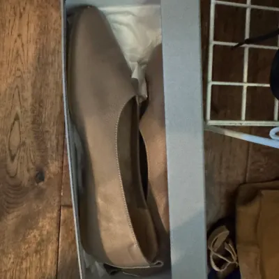 Sale Photo Thumbnail #229: Pair of women's taupe leather flat shoes, presented in their original grey shoebox with tissue paper.