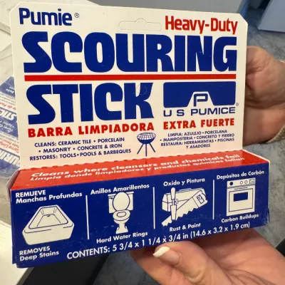 Sale Photo Thumbnail #123: Pumie Heavy-Duty Scouring Stick in its original cardboard packaging, designed for cleaning tile, porcelain, masonry, and concrete.