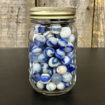 Sale Photo Thumbnail #759: A Collection of Blue and White Swirl Machine Made Glass Marbles in Graduated Jar