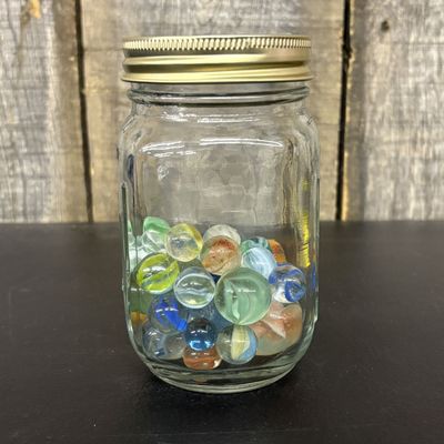 Sale Photo Thumbnail #312: An Assortment of Glass Marbles Stored in a Graduated Glass Jar