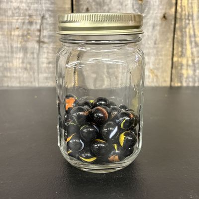 Sale Photo Thumbnail #650: A Collection of Black Glass Cat Eye Marbles in a Graduated Glass Jar