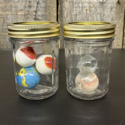 Sale Photo Thumbnail #769: A Collection of Five Glass Shooter Marbles in Two Jars