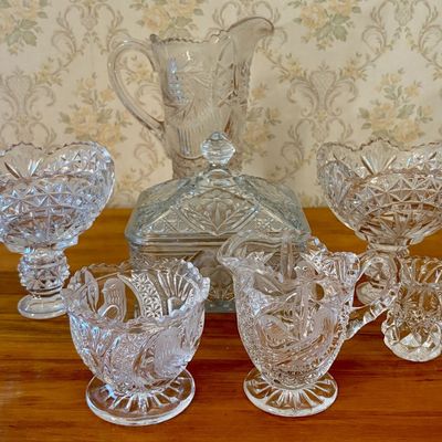 Sale Photo Thumbnail #566: A Collection of Pressed Glass Tableware Including a Pitcher, Covered Dish, and Accessory Vessels