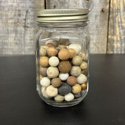Sale Photo Thumbnail #553: A Collection of Antique Clay and Earthenware Marbles in a Glass Measuring Jar