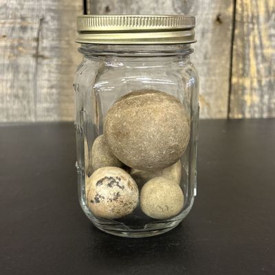 Sale Photo Thumbnail #433: A Group of Five Spherical Stone Game Balls or Projectiles in a Glass Jar