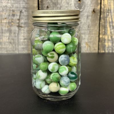 Sale Photo Thumbnail #760: A Collection of Green and White Machine Made Glass Marbles in a Graduated Utility Jar