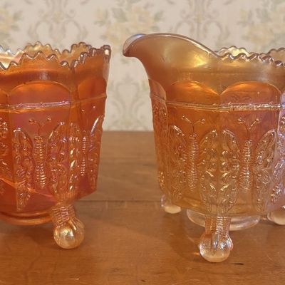 A Pair of Marigold Carnival Glass Butterfly and Berry Creamer and Open Sugar Bowl