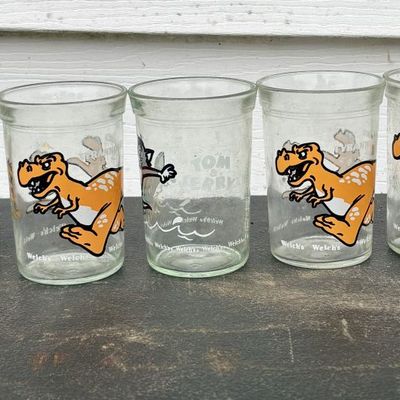 Sale Photo Thumbnail #794: A Collection of Seven Vintage Welch's Glass Jelly Jars Featuring Dinosaurs and Tom and Jerry