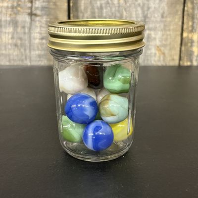 Sale Photo Thumbnail #761: A Collection of Assorted Glass Marbles in a Ribbed Glass Jar
