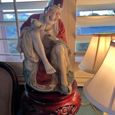 Vintage Chinese porcelain figurine depicting Ji Gong holding a fan, mounted on a carved wooden base.