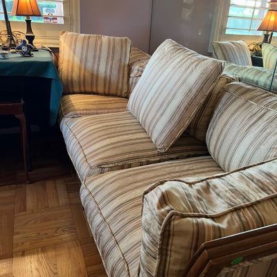 Traditional wooden-framed sectional sofa upholstered in a neutral striped fabric with matching accent pillows.