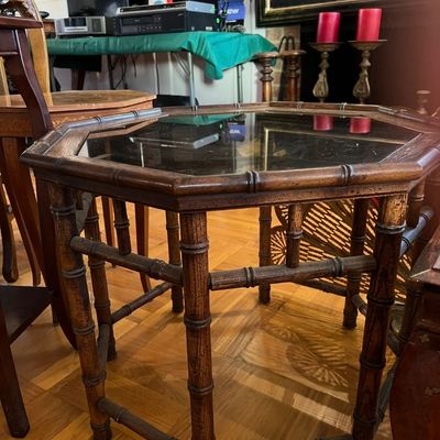 Faux bamboo octagonal side table with a glass insert top, displaying light surface wear.