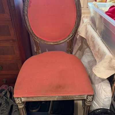 French Country style dining chair featuring a distressed whitewashed wooden frame, oval medallion back, fluted legs, and coral red fabric...