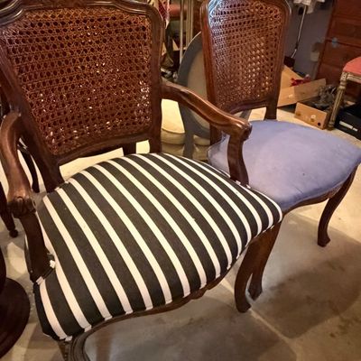 Pair of vintage French Provincial style cane-back armchairs featuring carved wood frames and mismatched upholstered seats.