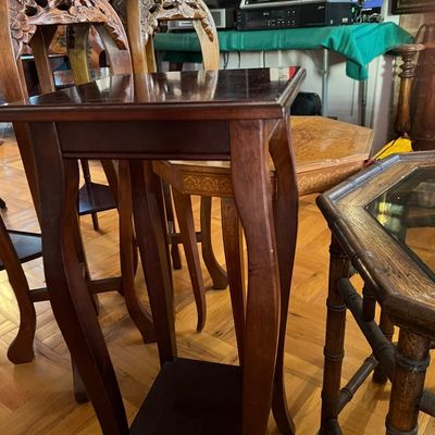 Tall dark wood accent plant stand with curved legs and a lower tier, displayed alongside other vintage side tables.