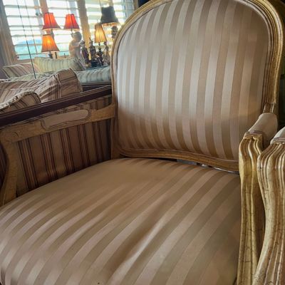 French Provincial style armchair featuring a carved, crackle-finish wooden frame and beige striped silk upholstery.