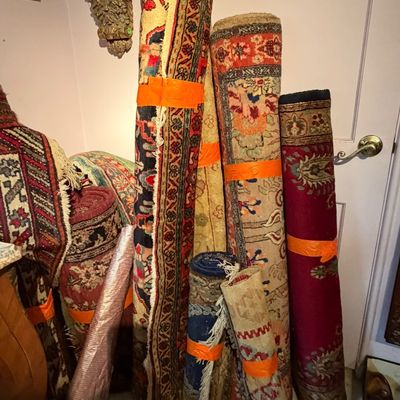 Collection of assorted rolled area rugs featuring traditional Persian and Oriental patterned designs in various sizes and colors.