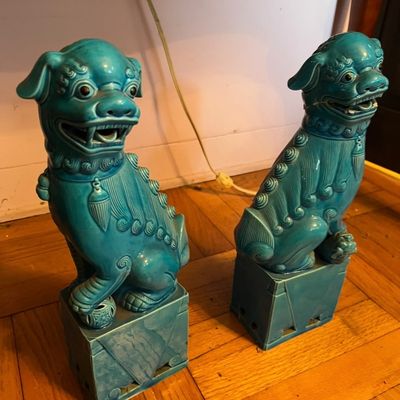 Pair of vintage turquoise glazed ceramic Chinese foo dog statues resting on plinth bases.