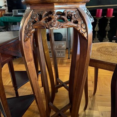 Hand-carved wooden plant stand featuring floral apron details and curved legs with an X-brace base.