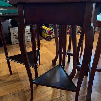Vintage dark wood two-tier plant stands featuring curved legs and triangular lower shelves.
