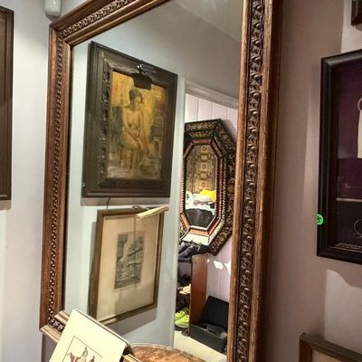 Large vintage wall mirror featuring a heavily carved dark wood frame with ornate egg-and-dart style details.