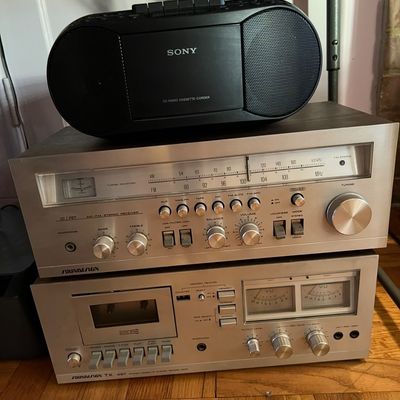 Vintage Soundesign audio stack featuring an AM/FM stereo receiver and a TX 497 cassette deck with dual VU meters, topped with a black...