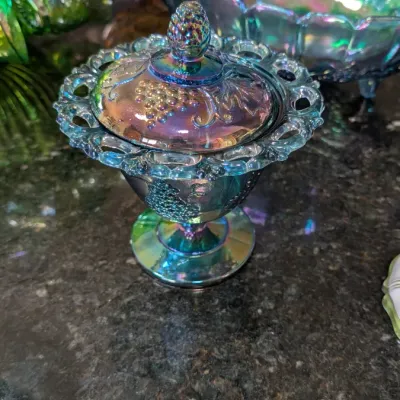 Sale Photo Thumbnail #2: Vintage blue carnival glass covered candy dish with a grape and cable pattern, featuring an openwork ruffled rim and a matching lid.