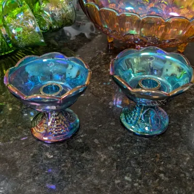 Sale Photo Thumbnail #6: Assorted vintage carnival glass tableware, including a pair of blue iridescent candle holders, a large amber footed bowl, and a green punch bowl set with matching cups.
