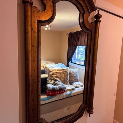 Sale Photo Thumbnail #11: Large wall mirror featuring an ornate, arched wooden frame with a distressed gold-toned finish and decorative side posts.